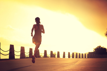 young fitness woman running on sunrise seaside trailの写真素材