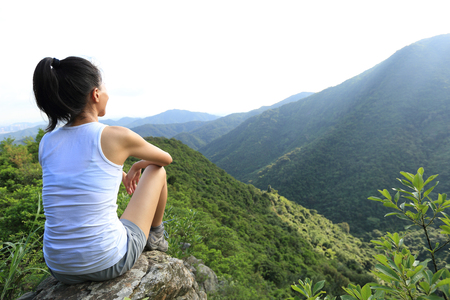 young woman enjoy the view at mountain peak cliffの写真素材