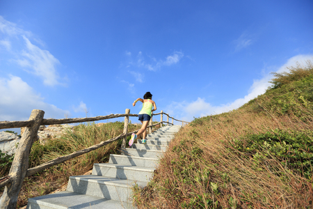 young fitness woman trail runner running up on mountain stairsの写真素材