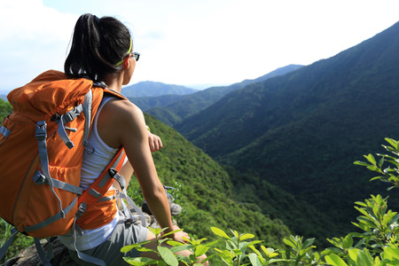 woman backpacker enjoy the view at mountain peak cliffの写真素材