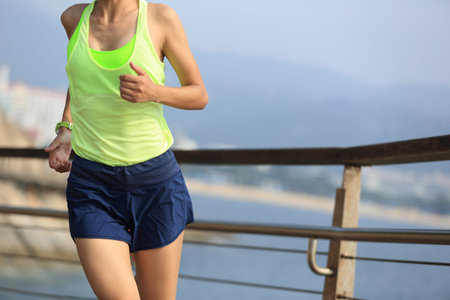 fitness sports woman running on wooden boardwalk seaside