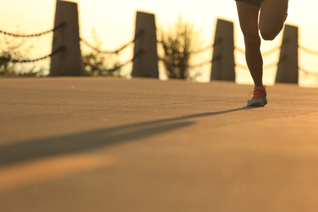 young fitness woman running on sunrise seaside trailの写真素材