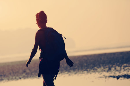 young woman hiking on sunrise beachの写真素材