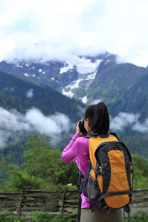 woman photographer taking photo with cell phone at mountain peak in tibet,chinaの写真素材