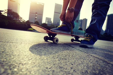 skateboarder tying shoelace at skate parkの写真素材