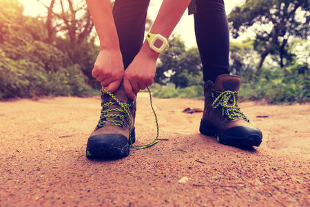 woman hiking tying shoelace on forest trail