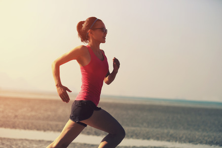 young fitness woman running at sunrise beachの写真素材