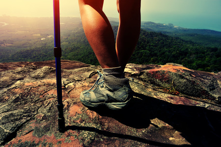 young woman hiker legs on mountain peak cliffの写真素材