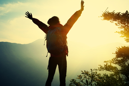 cheering woman hiker open arms at mountain peakの写真素材