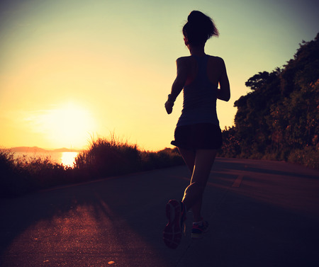 young fitness woman running on sunrise seaside trail,vintage effectの写真素材