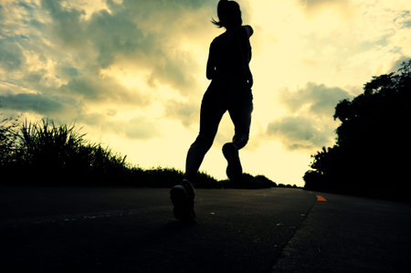 Runner athlete running at seaside road. woman fitness silhouette sunrise jogging workout wellness concept.の写真素材