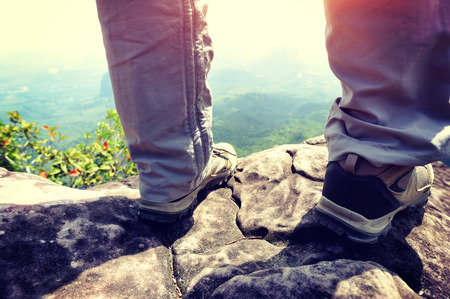 young woman hiker legs on mountain peak cliffの写真素材
