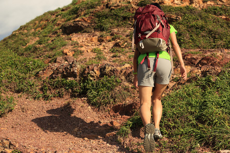 young woman backpacker climbing on  seaside mountain trailの写真素材