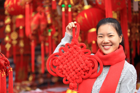 young asian woman with red chinese knot wishing you a happy chinese new yearの写真素材