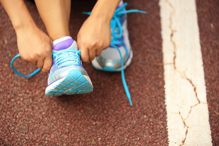 young woman runner tying shoelaces