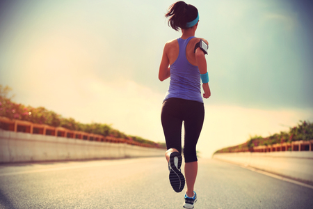 young woman runner running on city roadの写真素材