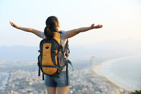hiking woman stand seaside rock looking the view with arms openの写真素材