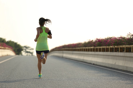 young woman runner running on city roadの写真素材