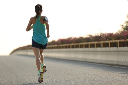 young woman runner running on city bridge roadの写真素材