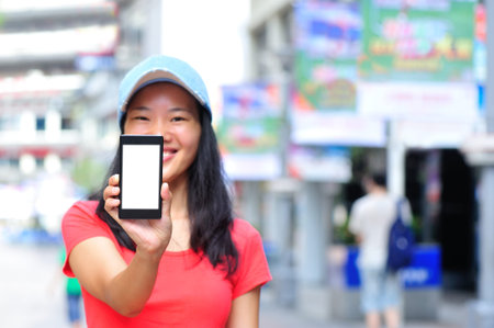 young asian woman holding blank smart phone on shopping street