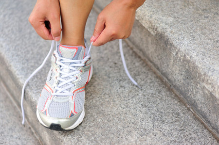 young woman runner tying shoelaces on stairs