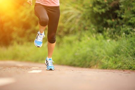 young fitness woman running at forest trail