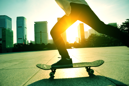 woman skateboarder skateboarding at sunrise cityの写真素材