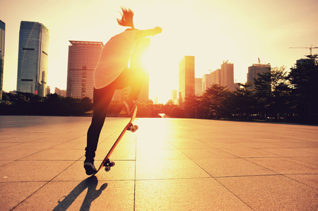 young woman skateboarding at sunrise cityの写真素材