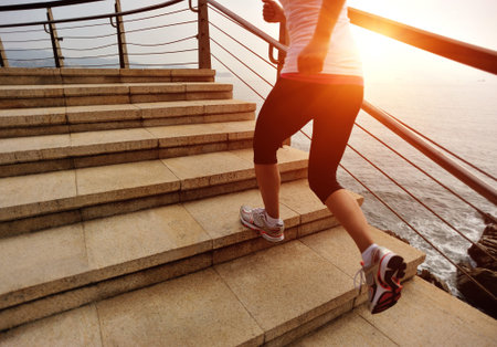sports woman running on stone stairs seaside