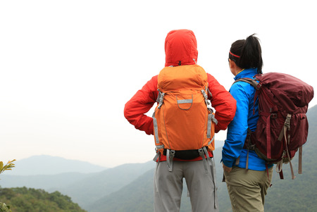 two successful backpacker enjoy the beautiful landscape at mountain peakの写真素材