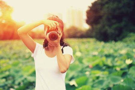 young woman photographer taking photo of blooming lotus at park