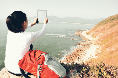 Woman taking pictures with tablet seasideの写真素材