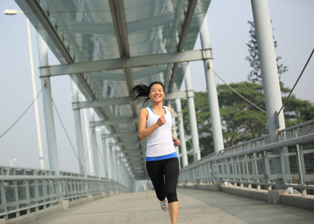 beautiful healthy lifestyle young asian woman running at modern city footbridge