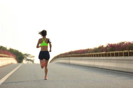 young fitness woman running at city roadの写真素材
