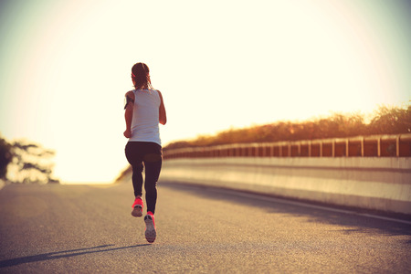 young sports woman runner running on city roadの写真素材