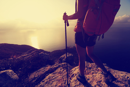 young woman backpacker at sunrise seaside mountain peakの写真素材