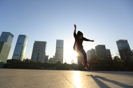 skateboarder doing an ollie trick at sunrise cityの写真素材