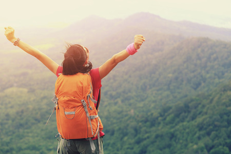 cheering woman hiker open arms at mountain peakの写真素材