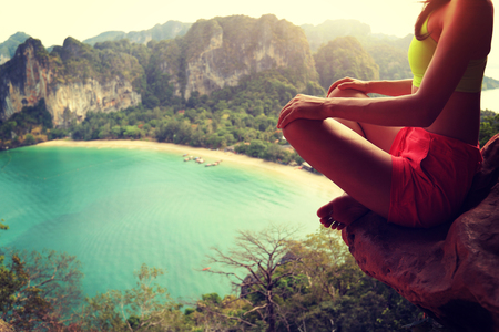 young woman practice yoga on mountain peak cliffの写真素材