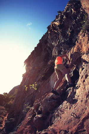 young woman rock climber climbing at seaside mountain cliffの写真素材