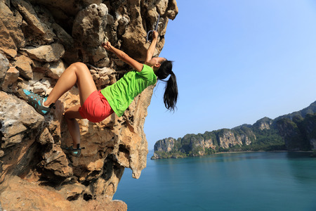 young woman rock climber climbing at seaside mountain rockの写真素材