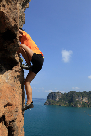 young woman rock climber climbing at seaside mountain rockの写真素材