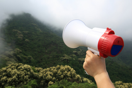 hand hold loudspeaker to blue sky on mountain peakの写真素材