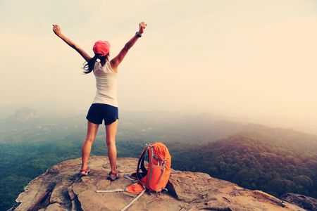 cheering woman hiker open arms at mountain peakの写真素材