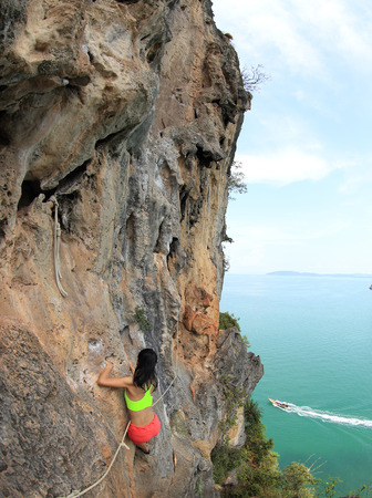 young woman rock climber climbing at seaside mountain rockの写真素材