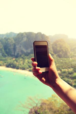 hand taking photo with smartphone at seasideの写真素材