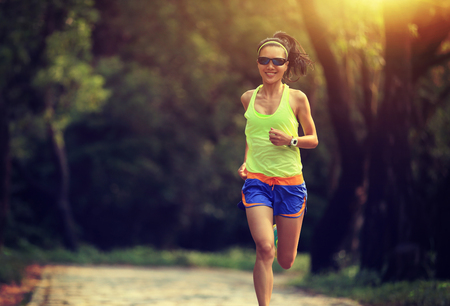 Runner athlete running on forest trail. woman fitness jogging workout wellness concept.の写真素材