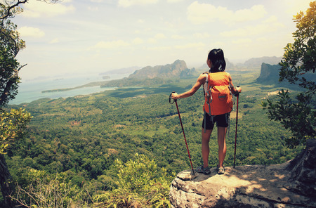 young woman backpacker hiking on seaside mountain peakの写真素材