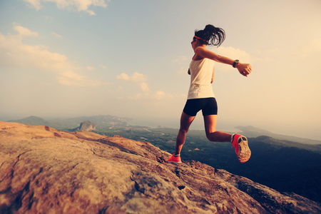 young woman trail runner running on mountain peakの写真素材