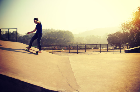skateboarding woman riding skateboard at skatepark rampの写真素材